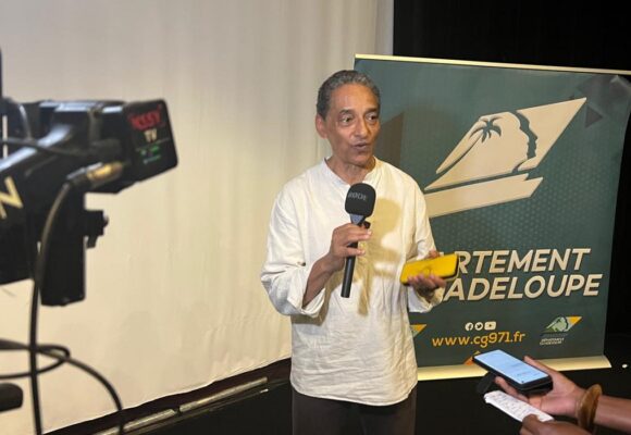 Serge Romana, président du Comité de la marche du 23 mai 1998 et coprésident du comité de pilotage du futur Mémorial national des noms des victimes de l’esclavage colonial, présente le 23 décembre 2025 au Mémorial Acte à Pointe-à-Pitre, les plans architecturaux et paysagers du projet. Photo : Le Courrier de Guadeloupe