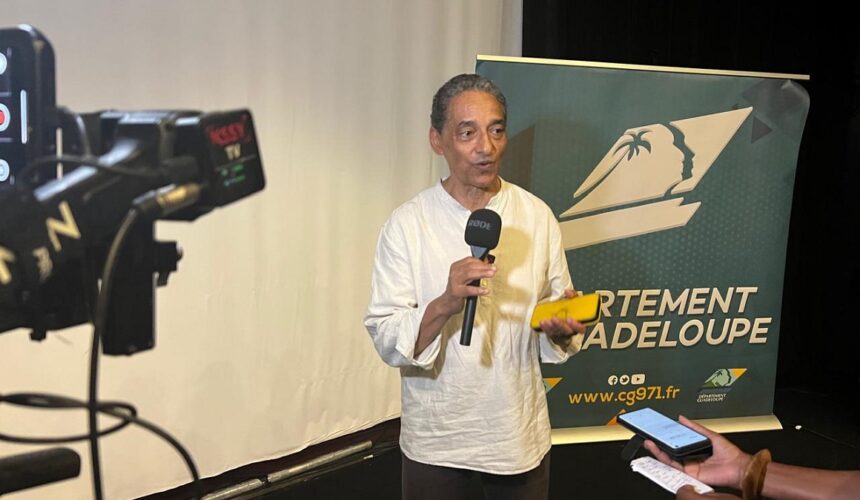 Serge Romana, président du Comité de la marche du 23 mai 1998 et coprésident du comité de pilotage du futur Mémorial national des noms des victimes de l’esclavage colonial, présente le 23 décembre 2025 au Mémorial Acte à Pointe-à-Pitre, les plans architecturaux et paysagers du projet. Photo : Le Courrier de Guadeloupe